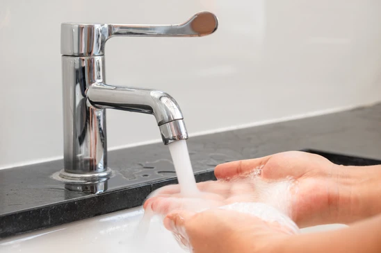 Personne buvant un verre d'eau claire, tenant le récipient en verre transparent près de sa bouche