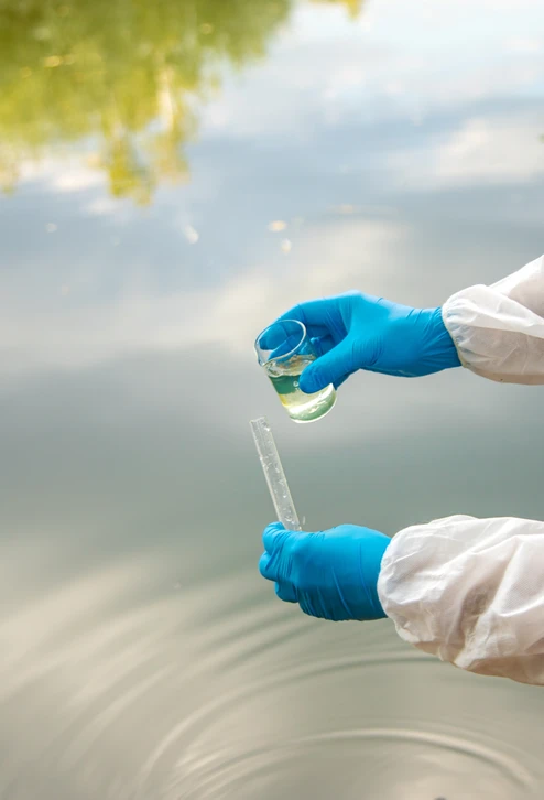 Laboratoire alimentaire avec technicienne en tenue stérile complète analysant échantillons liquides jaunes
