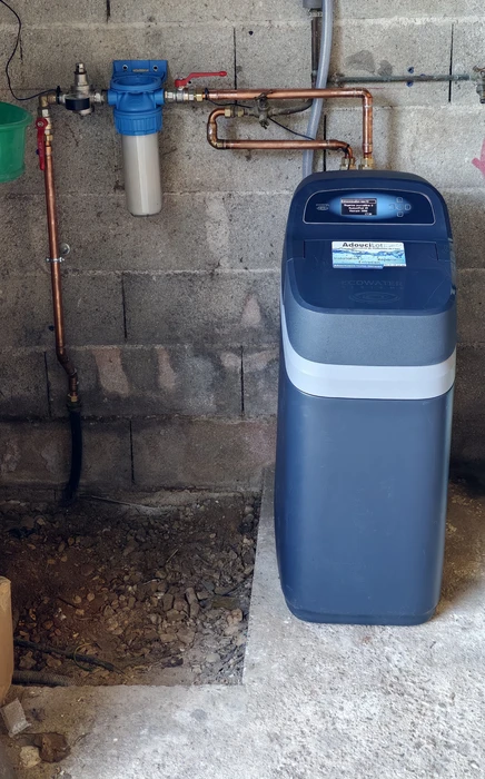 Une main installe un filtre à eau domestique sur un robinet de cuisine en inox