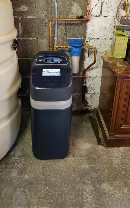 Technicien en combinaison bleue installant un système de filtration d'eau sous évier de cuisine moderne